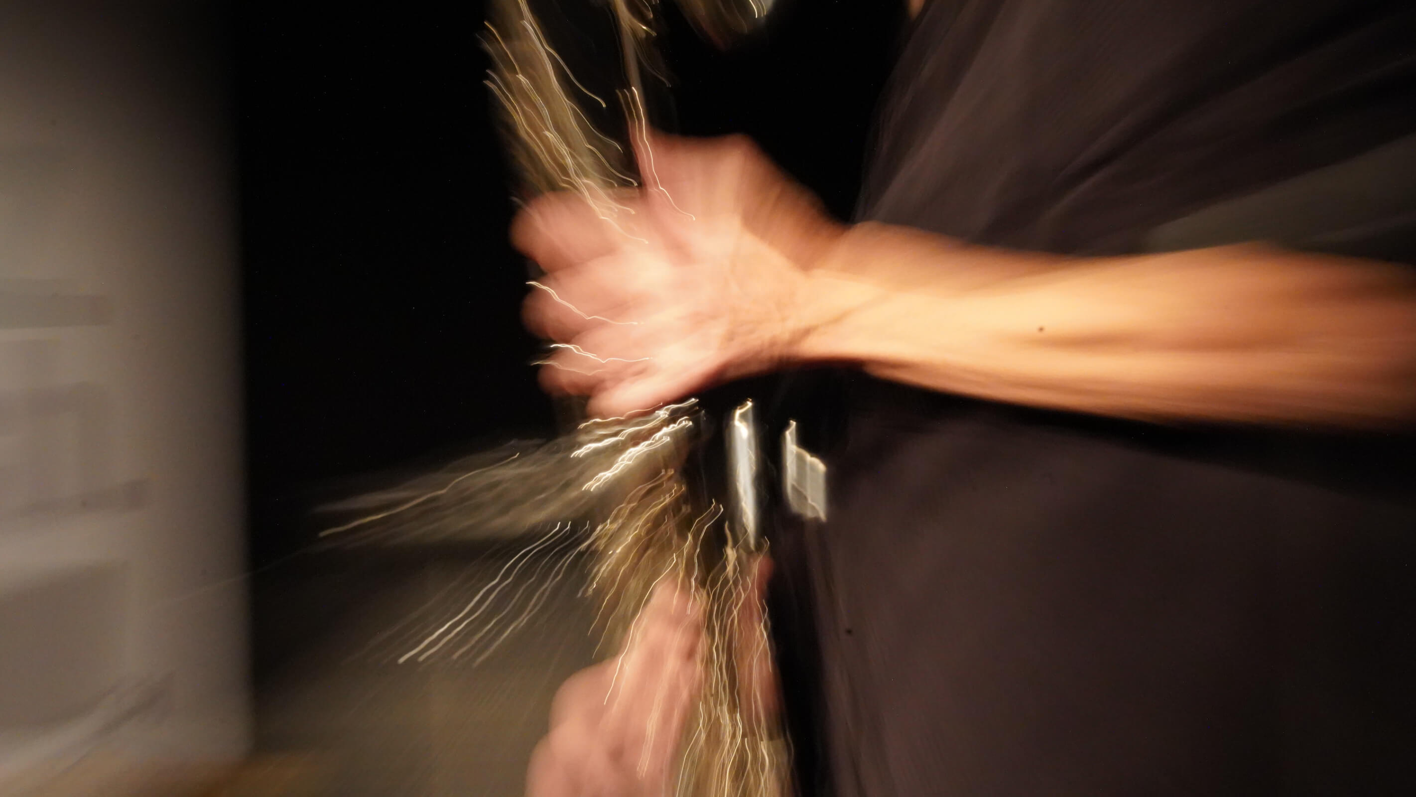 Klarinettistin mit geschlossenen Augen im warmen Bühnenlicht, Instrument abwärts.