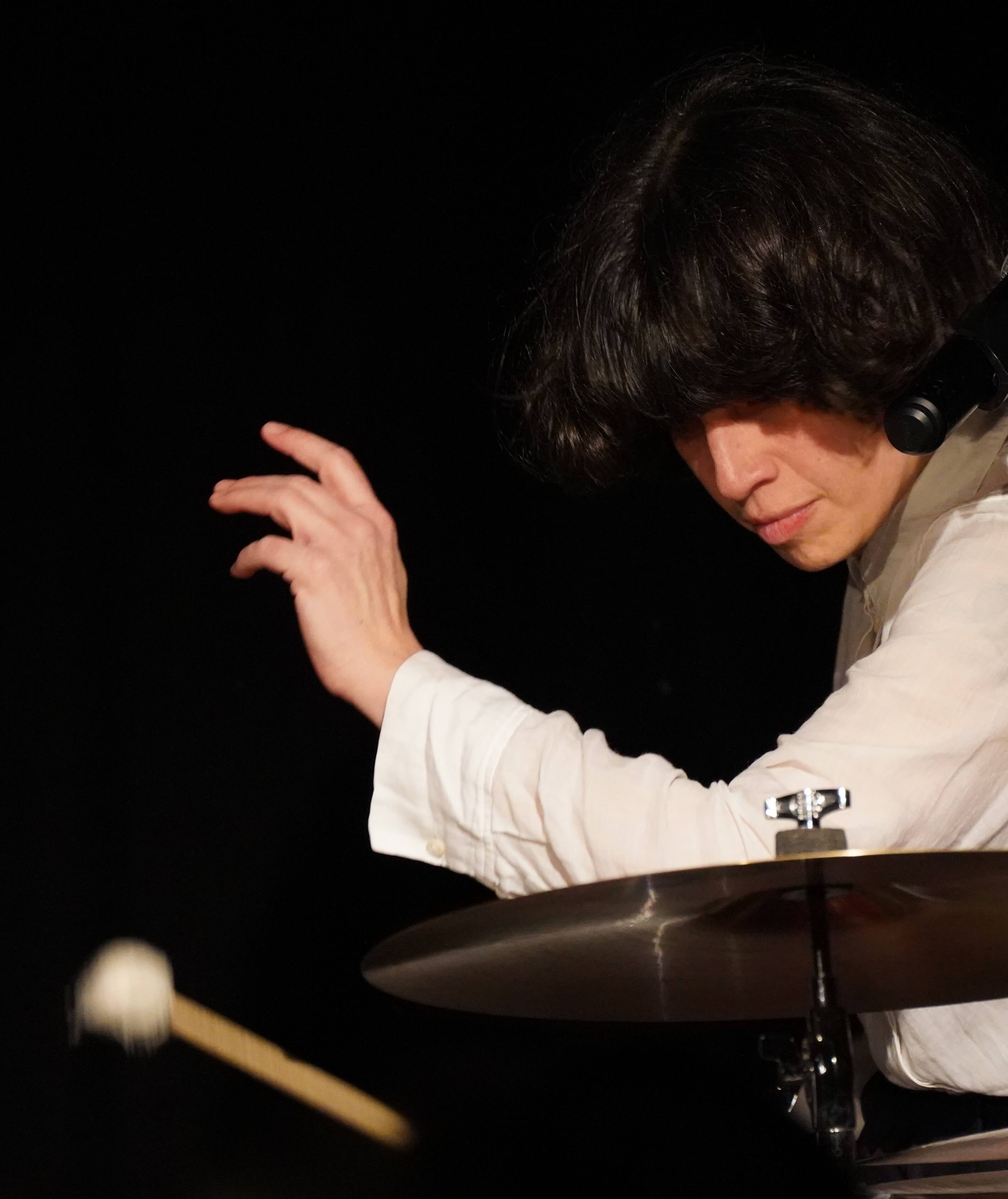 Schlagzeugerin im hellen Shirt schlägt ein Becken, Schlegel verwischt.