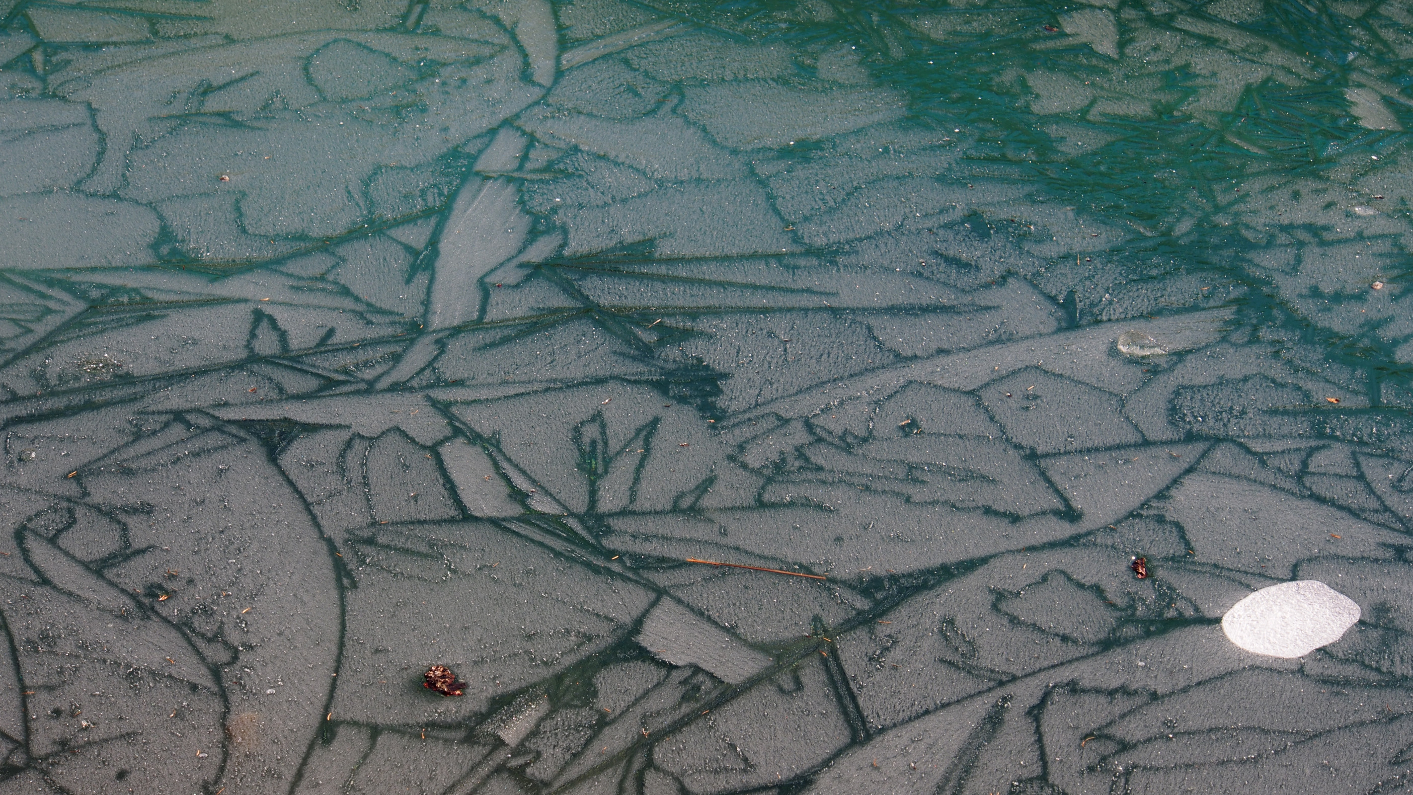 Geometrische Risse im Eis auf türkisfarbenem See