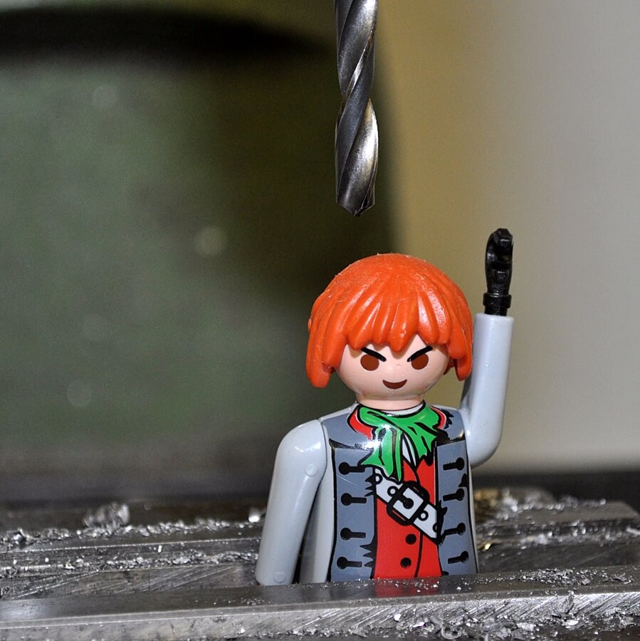 Playmobil-Piratenfigur unter einem schwebenden Bohrer, umgeben von Metallspänen.