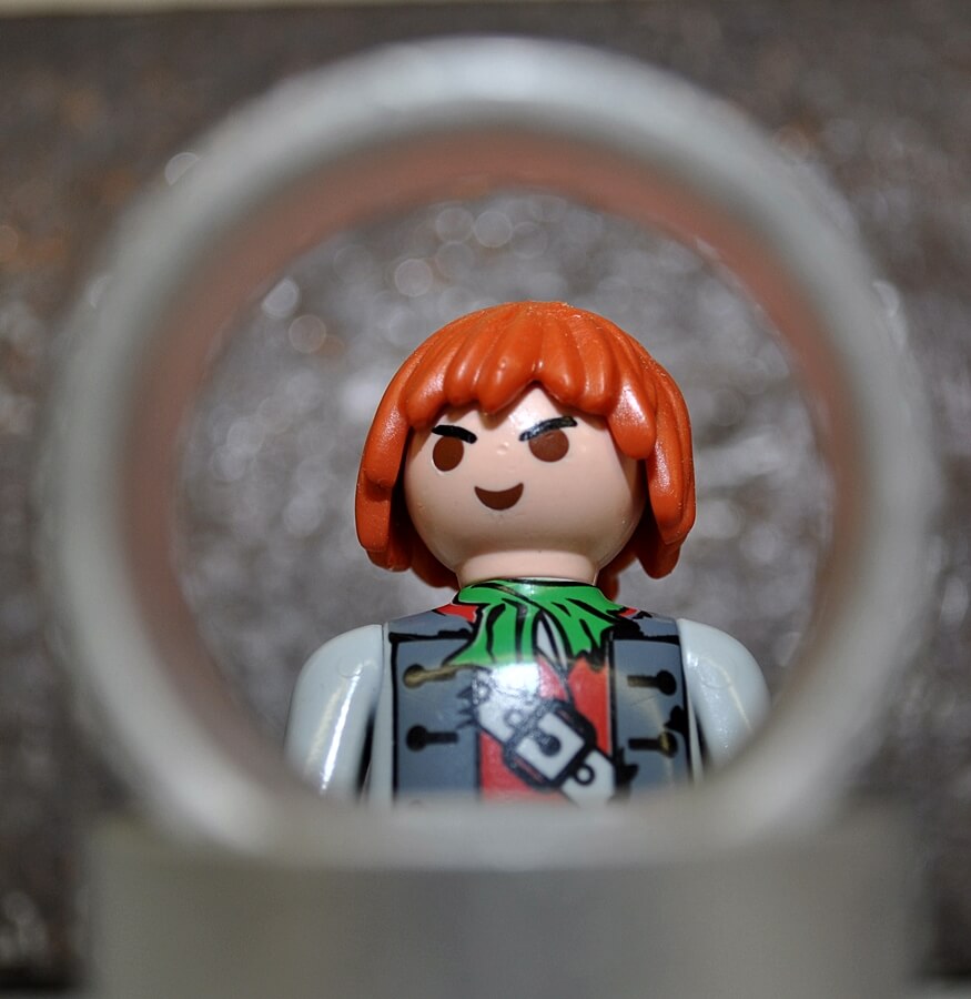 Playmobil-Piratenfigur, eingerahmt von einem Metallring vor strukturiertem Hintergrund.